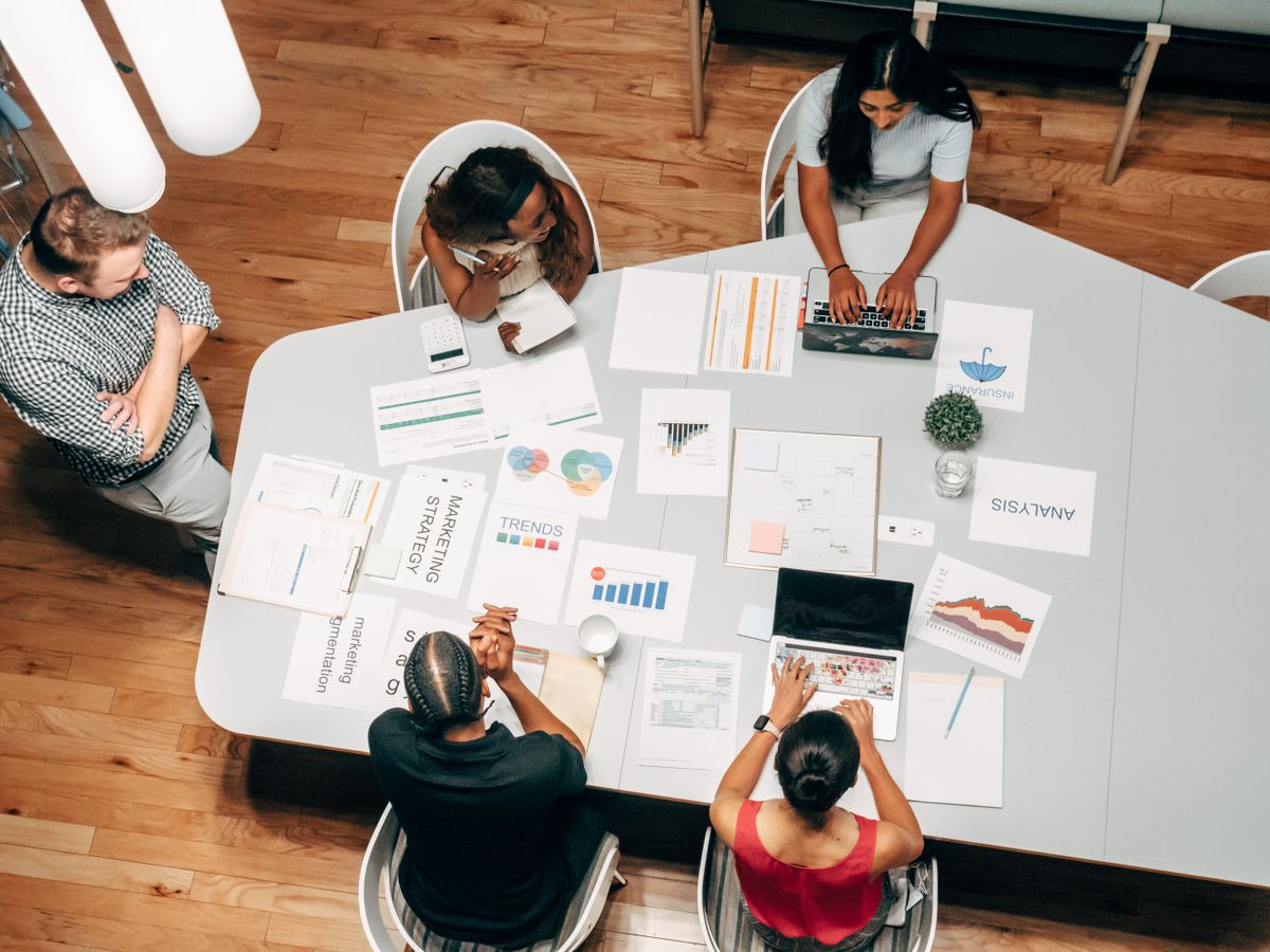 Overhead view of colleagues reviewing strategy documents, charts, and laptops around a conference table